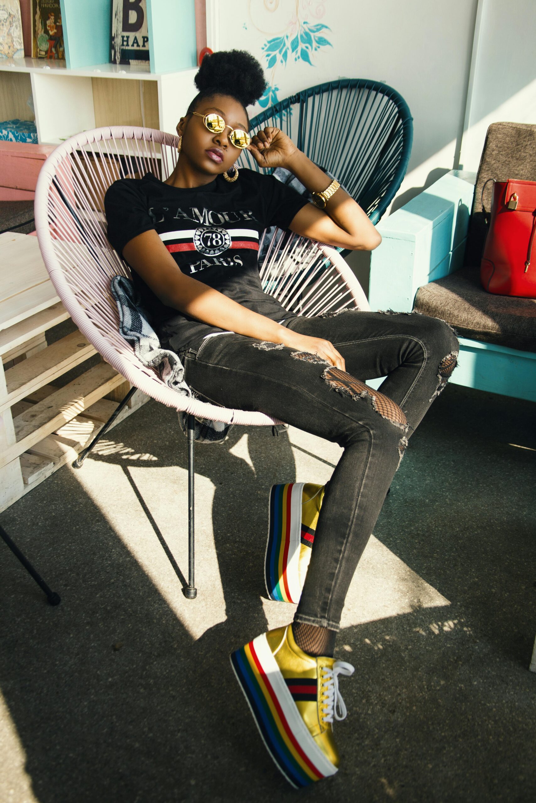 Stylish woman with sunglasses relaxes in a colorful room. Fashion and cool vibes.